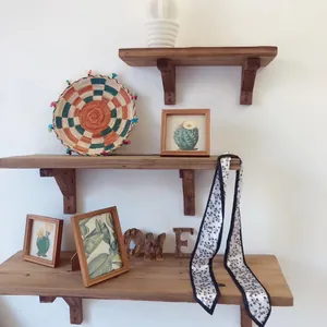 Détail d'un foulard twilly noir et blanc à fleurs sur un support en bois