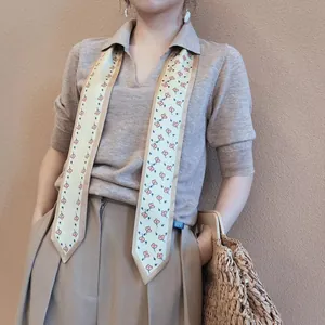 Close-up of floral skinny scarf tied as a decorative neckerchief on a knit polo shirt