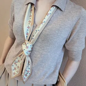 Detail of a narrow silk scarf with floral patterns worn around the neck for a stylish look