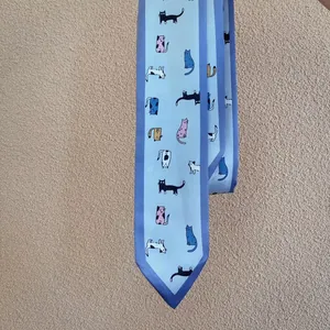 Detail van lichtblauwe smalle zijden sjaal met kleurrijke cartoonkatten en marineblauwe rand