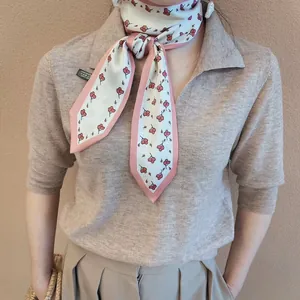 Elegant narrow scarf with cherry pattern and pink edges paired with a knit polo shirt