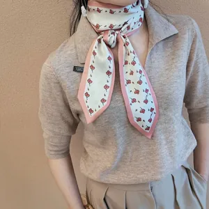 Detail of a thin silk scarf tied as a necktie with red cherry print and pink edges