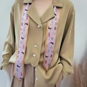Detail van roze zijden sjaal met kattenprints gecombineerd met een kaki chiffon shirt