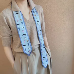 Detail van een blauwe zijden twilly sjaal met kleurrijke kattenprints gedragen door model