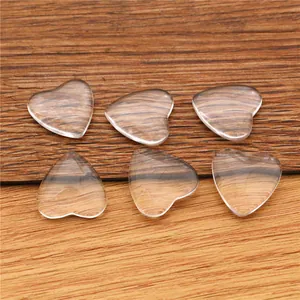 Detailed view of six clear heart-shaped glass cabochons on a rustic wooden background