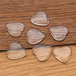 Macro shot of seven transparent heart shaped glass cabochons on wood for DIY jewelry making
