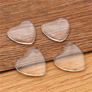 Clear heart-shaped glass cabochons for DIY jewelry making on natural wooden background