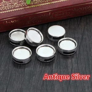 Macro view of 6 antique silver DIY jewelry round base trays on a vintage wood background