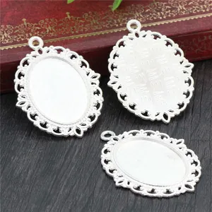 Three pieces of vintage silver oval cameo settings with filigree edges on a rustic desk