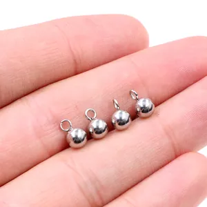 Polished stainless steel ball stud earrings with hanging loops shown on fingertips