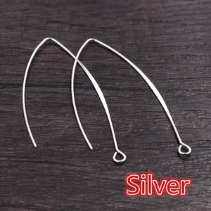 Detailed view of silver-plated V-shaped earring hooks on dark wood background