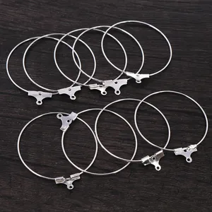 Set of 10 silver DIY hoop earring findings for jewelry making on dark wood background