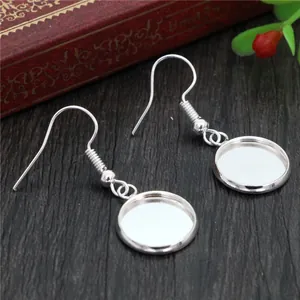 DIY silver earring hooks with round blank trays on a vintage wood background
