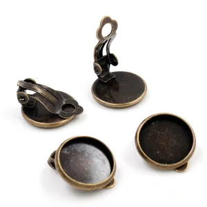 Close-up of four antique bronze DIY earring clips with round tray bases for jewelry making
