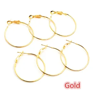 Trois paires de boucles d'oreilles créoles dorées brillantes sur fond blanc épuré