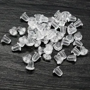 Topes de silicona transparente para pendientes sobre fondo de madera negra para joyas