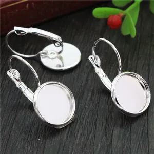 Three silver French ear hooks with blank round bezel settings on a wood surface