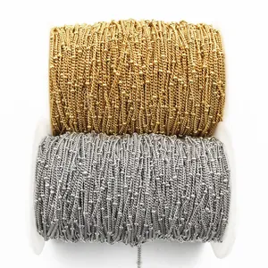 Detailed macro of gold and silver stainless steel bead chains on white plastic spools