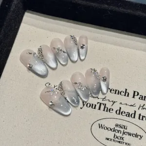 Handmade almond nails with grey-blue cat eye gradient and sparkly rhinestone accents