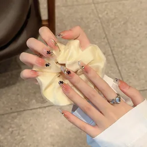 Coffin press-on nails with gradient nude base, black floral patterns and gold accents