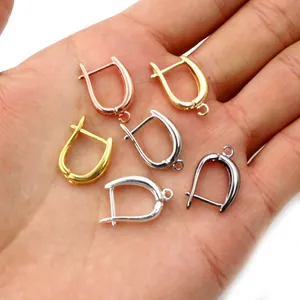 Ganchos para pendientes en forma de U de cobre en varios acabados metálicos sobre una palma