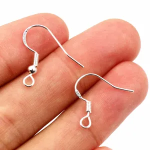 Close-up of S925 sterling silver fish hook earring wires for jewelry making on fingers