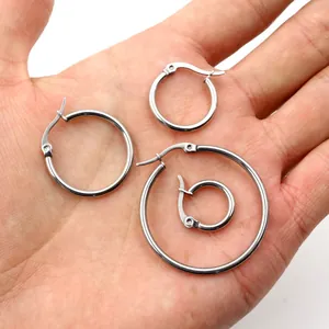 Set of four polished stainless steel hoop earrings in various sizes on palm of hand