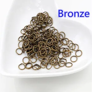 200 anellini aperti in bronzo per gioielli in un piatto di ceramica bianca a forma di cuore