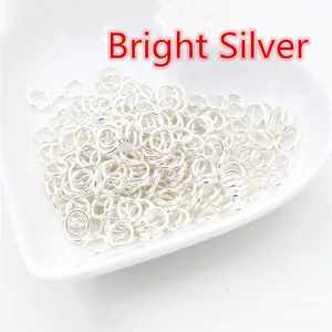 Primo piano di anellini aperti in argento lucido per gioielli fai-da-te in piatto bianco