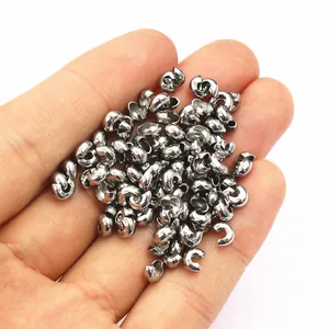 Close-up of stainless steel crescent moon crimp beads for jewelry making in hand