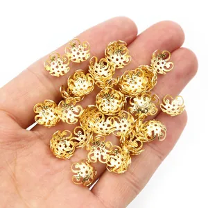 Nahaufnahme goldener hohler Blumen-Perlenkappen auf einer Hand mit feinen Metalldetails