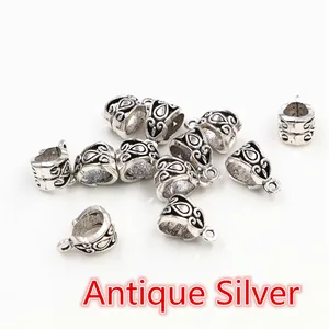 Macro detail of antique silver alloy bail beads with engraved floral scroll patterns