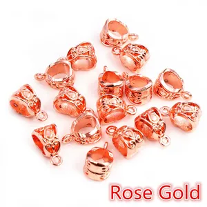 Macro detail of rose gold alloy bail connectors with hollow floral patterns for DIY jewelry
