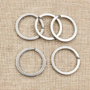 Detailed view of five polished stainless steel flat key rings on a textured background