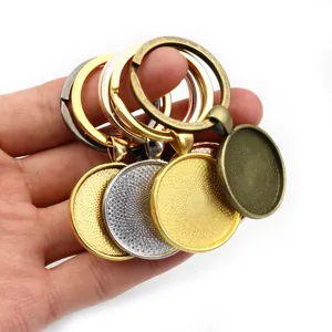 DIY keychain bezel pendants in assorted metal finishes held in hand for scale