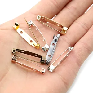 DIY jewelry metal safety pins in various metallic colors held in palm for size comparison