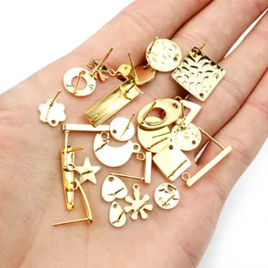 Various gold stainless steel earring posts with hanging loops held in hand for DIY jewelry
