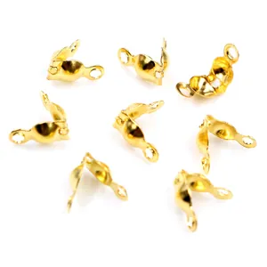Close-up of golden calotte crimps for DIY jewelry making spread on white background