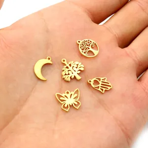 Five gold-plated stainless steel charms including moon, hamsa, and tree on a palm