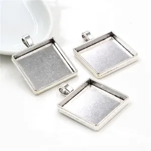 Three antique silver square alloy pendant trays for DIY jewelry making on white background
