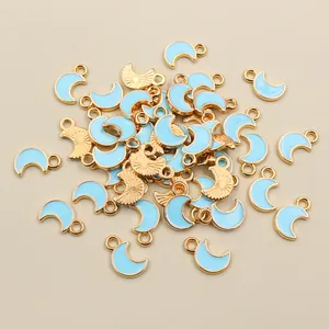 Detail of light blue enamel moon pendants with gold metal edges for DIY jewelry making