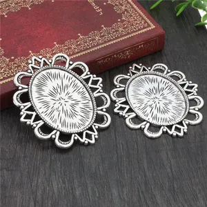 Macro view of two vintage 30x40mm silver oval pendant trays on dark wood background