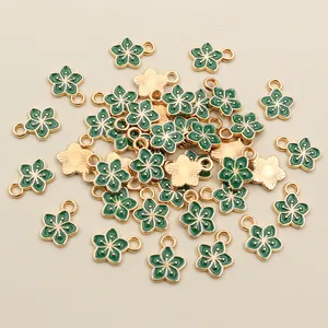 Close-up of DIY gold-plated flower charms with green enamel for jewelry making