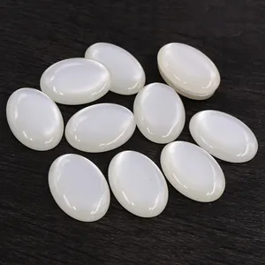 Macro detail of 10 white oval cabochon resin stones on a rustic wood background