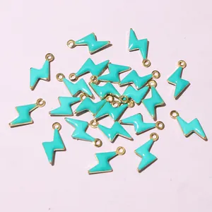 Macro shot of turquoise enamel lightning bolt charms with golden metal hooks for DIY jewelry