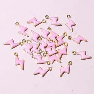 Macro shot of small pink enamel and gold lightning bolt pendants for DIY jewelry making