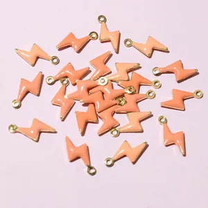 Detailed close-up of lightning bolt charms with pink enamel and gold-plated metal loops