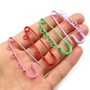 Detail shot of colorful safety pins with four loops held in hand for size comparison