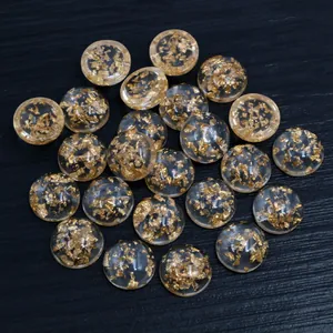 Nahaufnahme von runden Harz-Cabochons mit Goldfolienflocken auf dunklem Untergrund