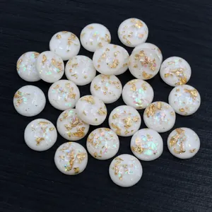 Makroaufnahme von Harz-Cabochons mit Goldfolie und irisierendem Glitzer auf Holz